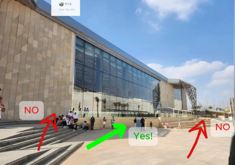 The image shows the front of the Khufu Solar boat museum viewed from the main Grand Egyptian Museum building. red arrows show the routes not to go, and a green arrow shows the route in the middle to find the Boat pit.