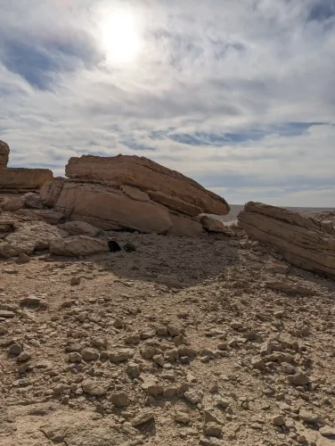 The image shows a desert landscape with large rocky outcrops and gravels of various sizes in the foreground.